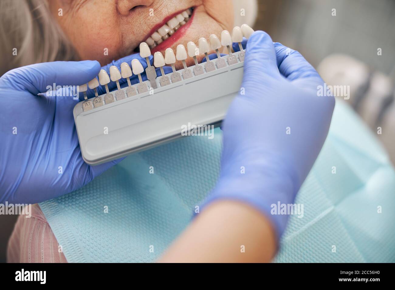 Arzt prüft und wählt die Farbe der Zähne in Der Zahnarztstuhl Stockfoto