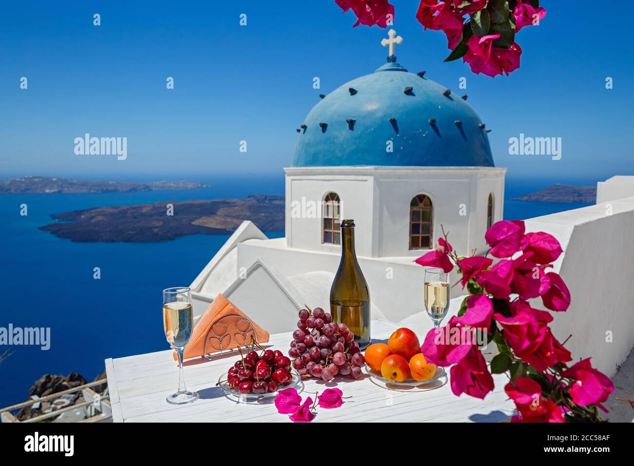 Wein und Obst für zwei auf dem Hintergrund des Meeres und der Insel Santorini. Stockfoto