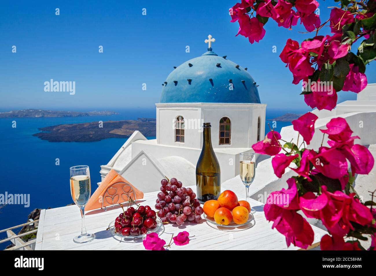 Wein und Obst für zwei auf dem Hintergrund des Meeres und der Insel Santorini. Stockfoto