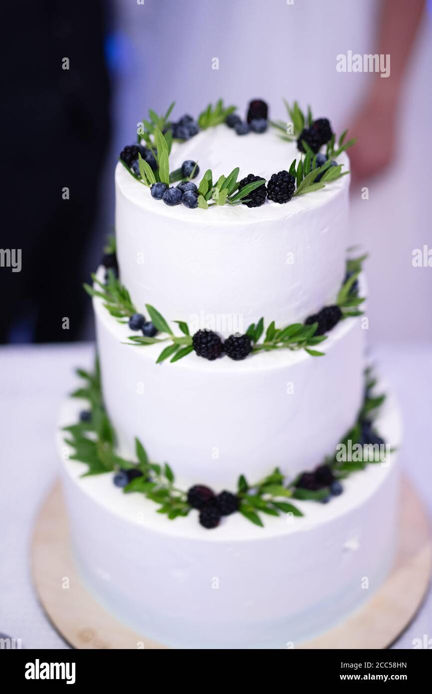 Weiße dreistufige Kuchen mit Brombeeren und Blättern , selektive Fokus , Hochzeitstorte dekoriert Stockfoto