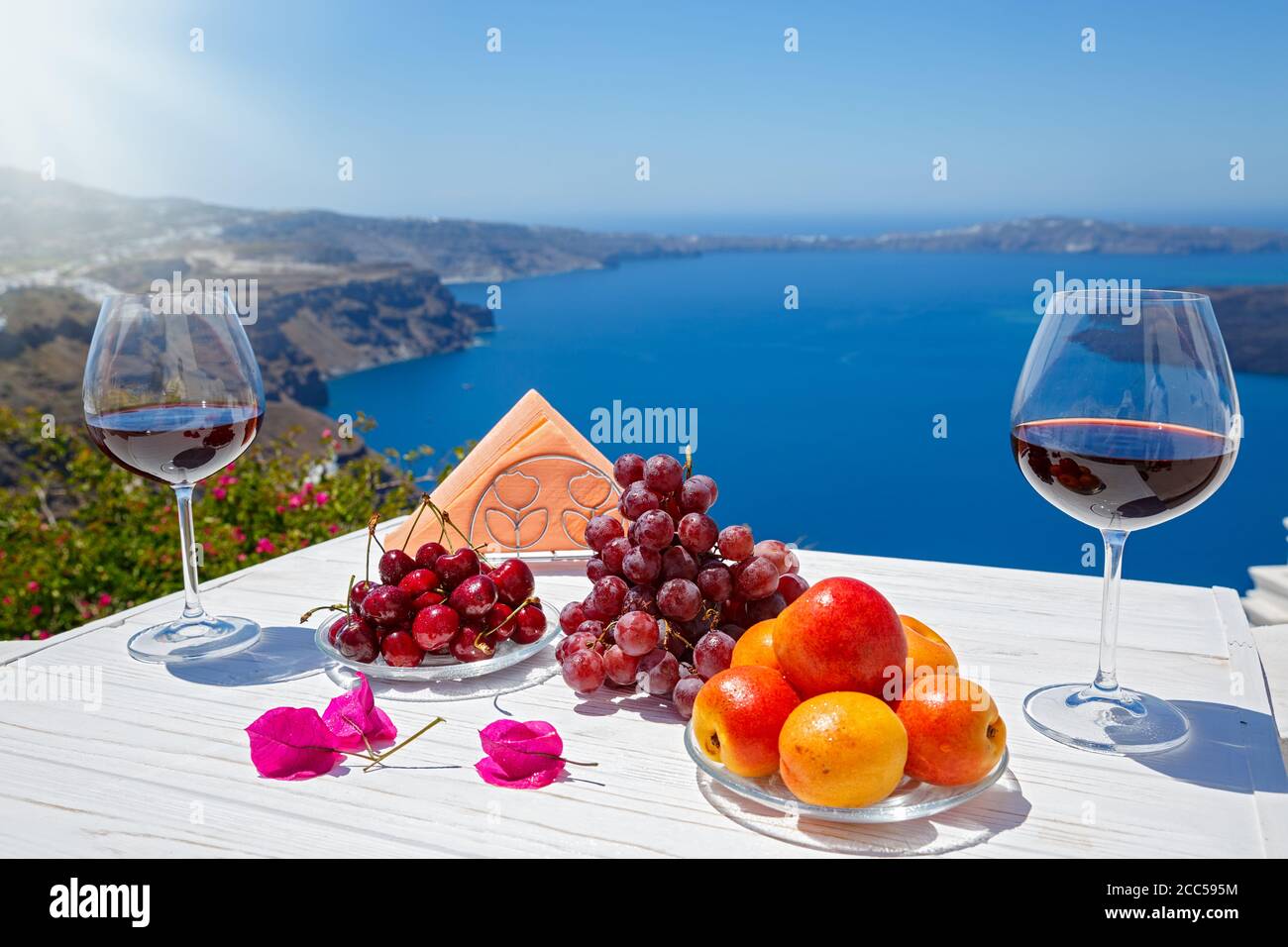 Obst und zwei Gläser Rotwein auf dem Hintergrund Vom Meer von Santorini Stockfoto