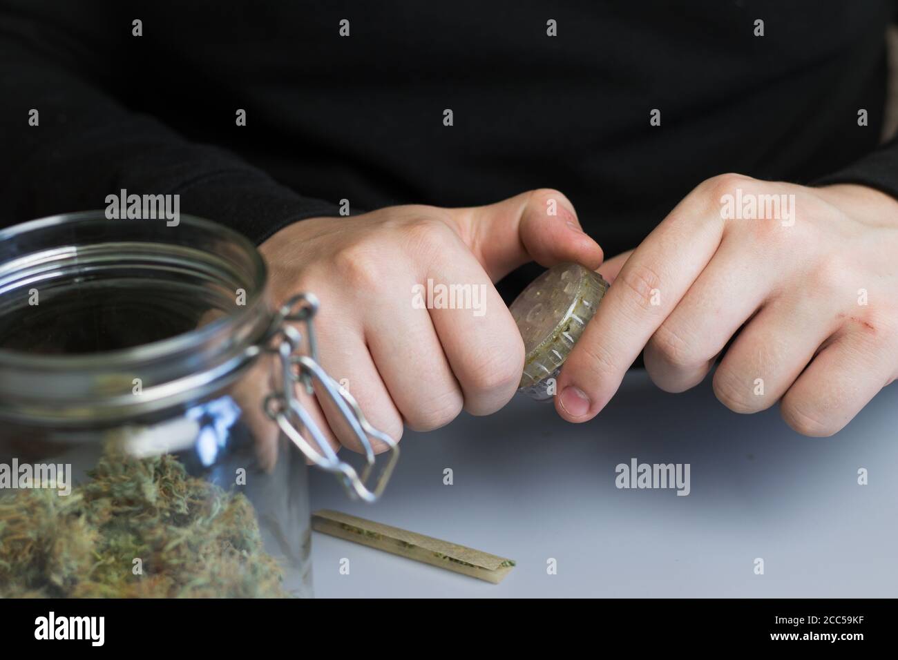 Cannabisknospen in der Mühle. Mann Hände mit Marihuana. Prozess des legalen Marihuanakonsums in der Medizin. THC-Kräuterbehandlung Stockfoto