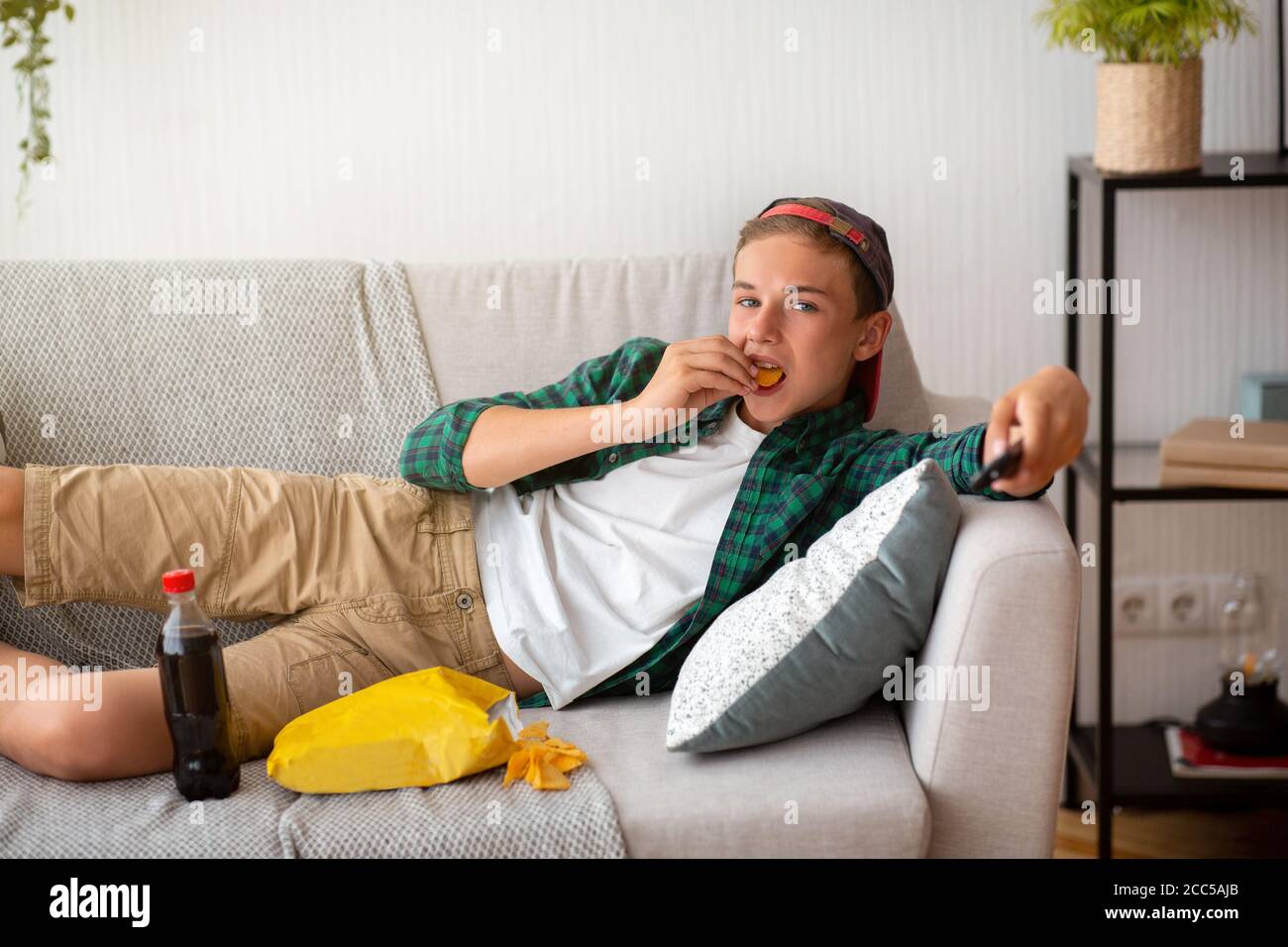 Teen Kerl essen Chips und Fernsehen zu Hause Stockfoto