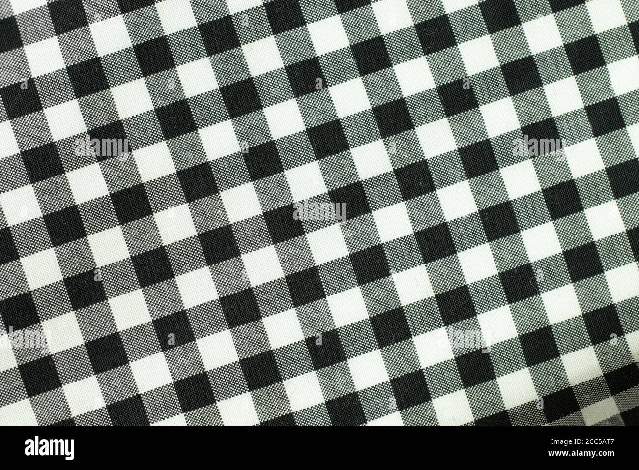 Zelle mit weißen, schwarzen und grauen Kontrollkästchen. Hintergrund mit Stofftextur Stockfoto