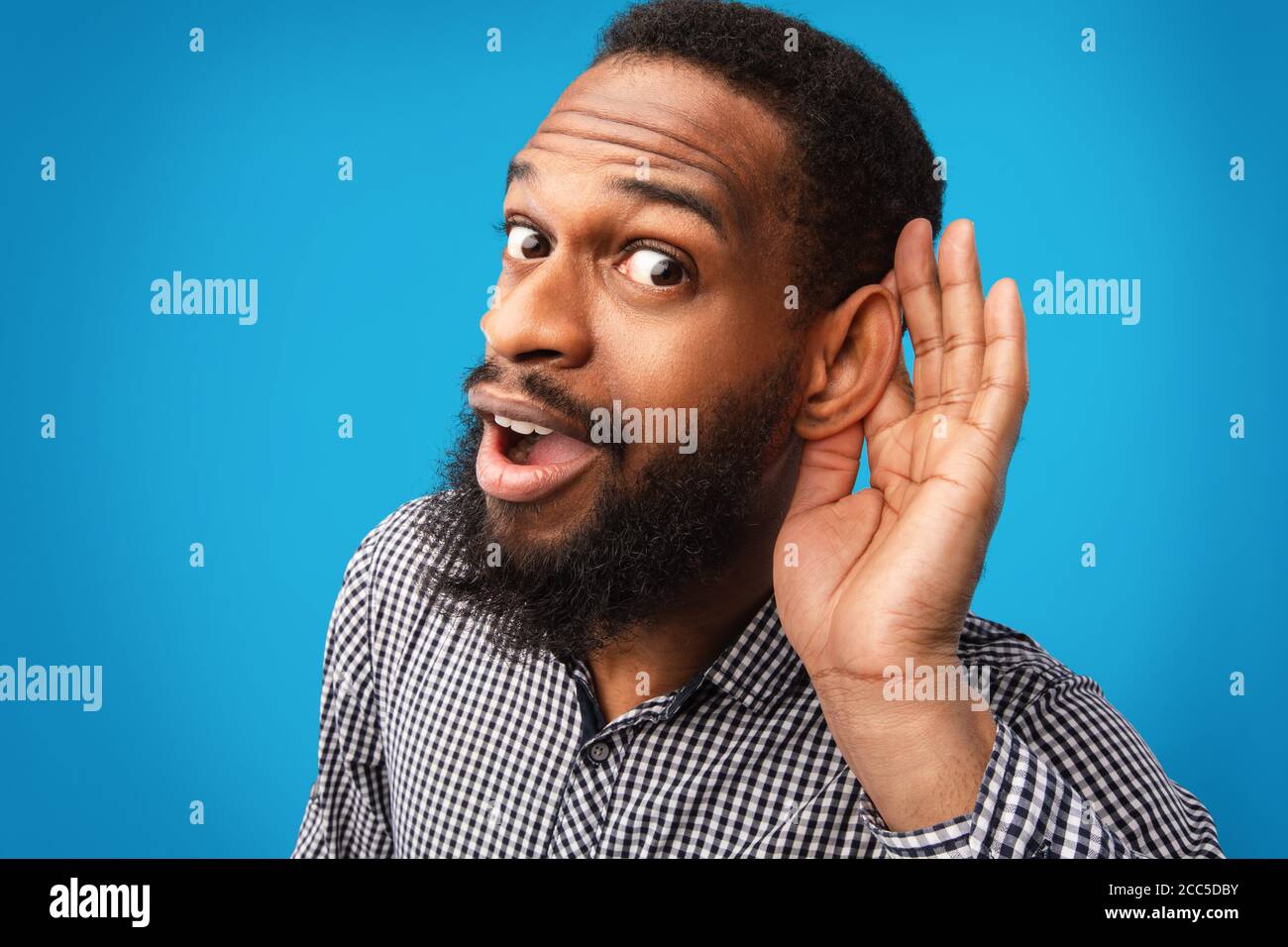 Neugierig stattlichen Afro Kerl hält Hand in der Nähe seines Ohrs Stockfoto