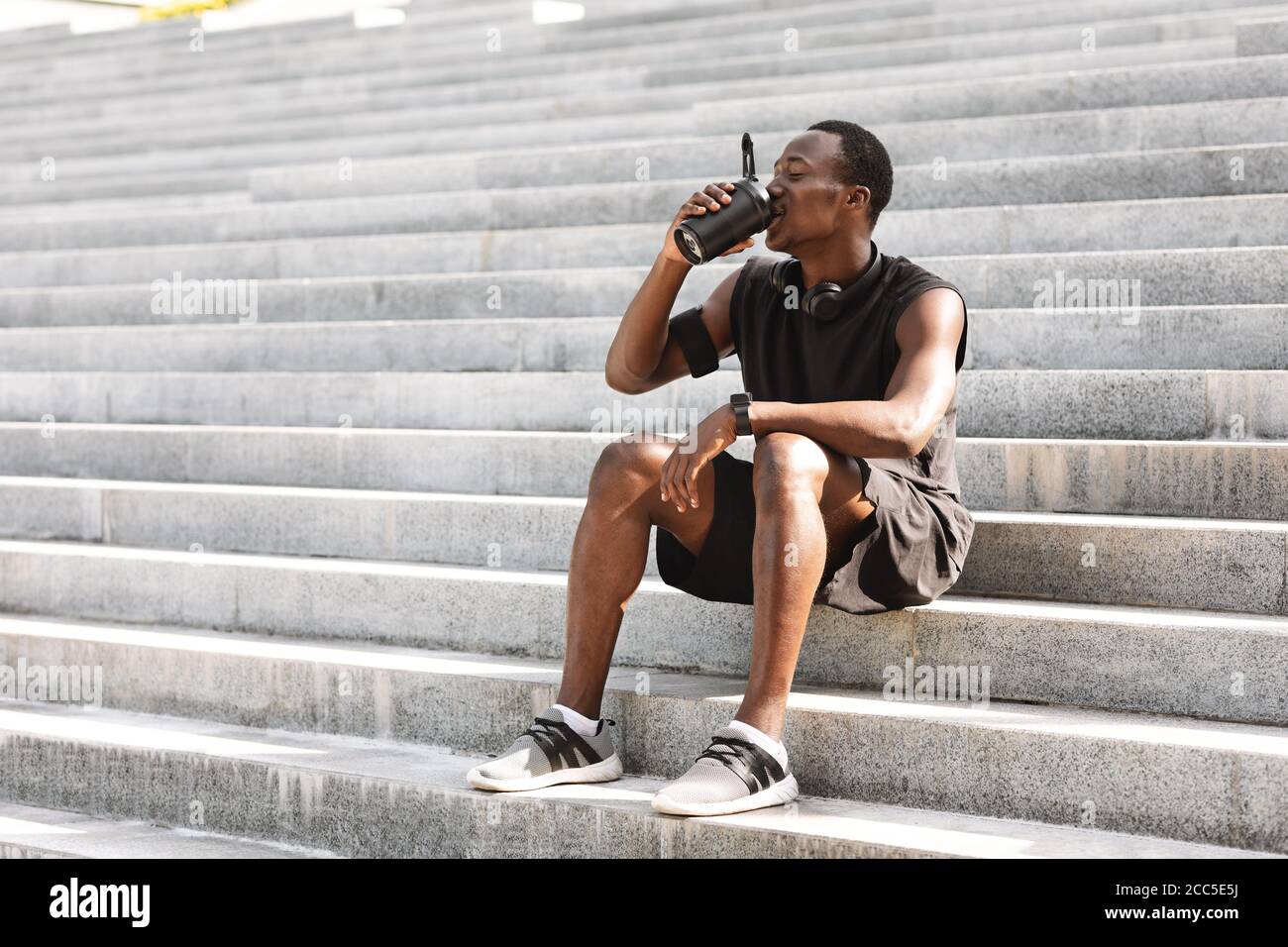 Thursty Black Männlich Athlete Trinkwasser, Ruhe Auf Urban Treppe Nach Dem Training Im Freien Stockfoto