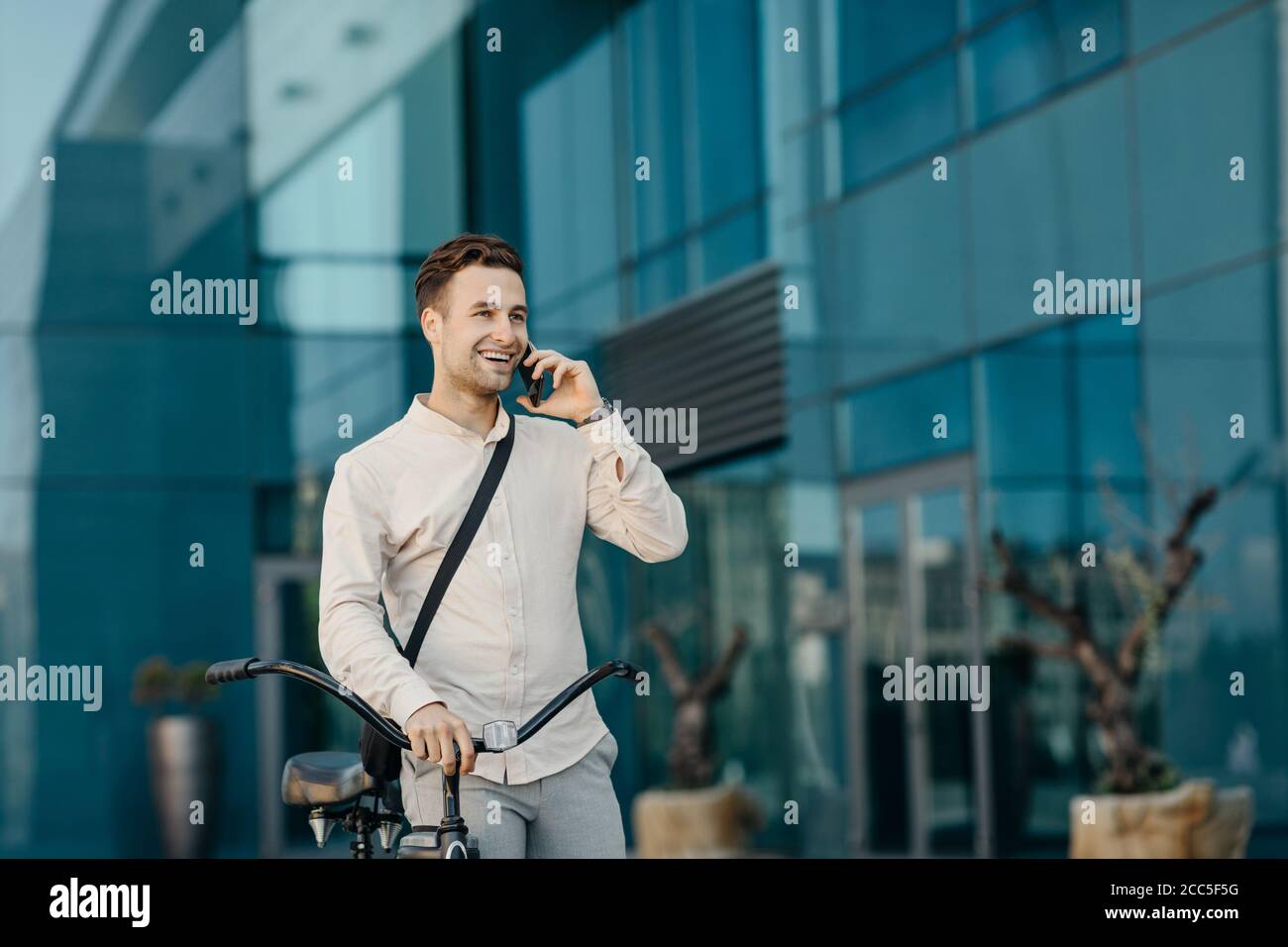 Geschäftsmann mit Stadtverkehr. Porträt eines Mannes mit Telefon, in der Nähe eines modernen Bürogebäudes Stockfoto