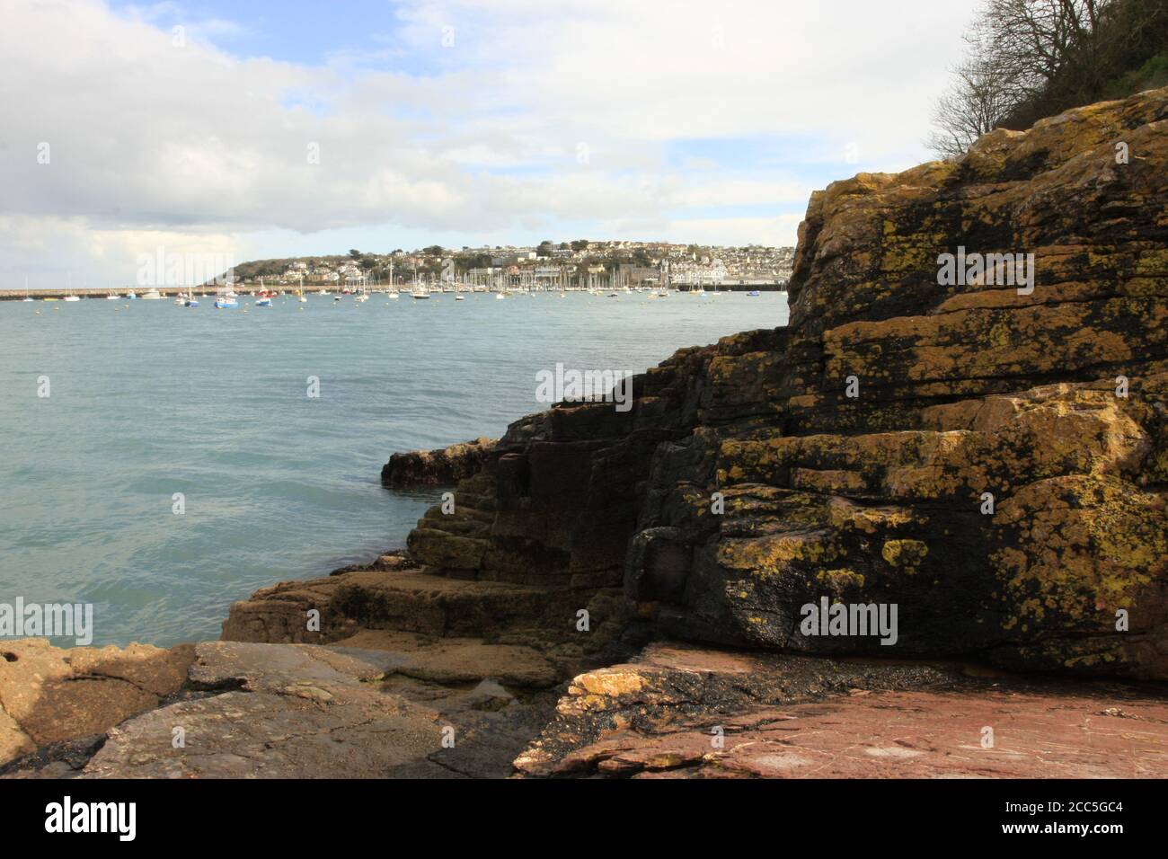 Blick auf den äußeren Hafen von Brixham von Battery Gardens, verankerten Booten, Kalksteinfelsen und Berry Head Stockfoto