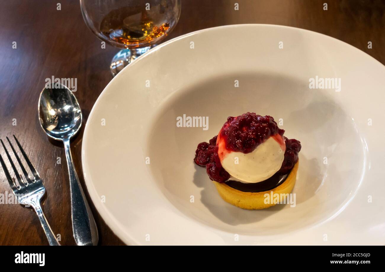 Schokoladentörtchen mit Himbeersoße und einem Schnaps Stockfoto