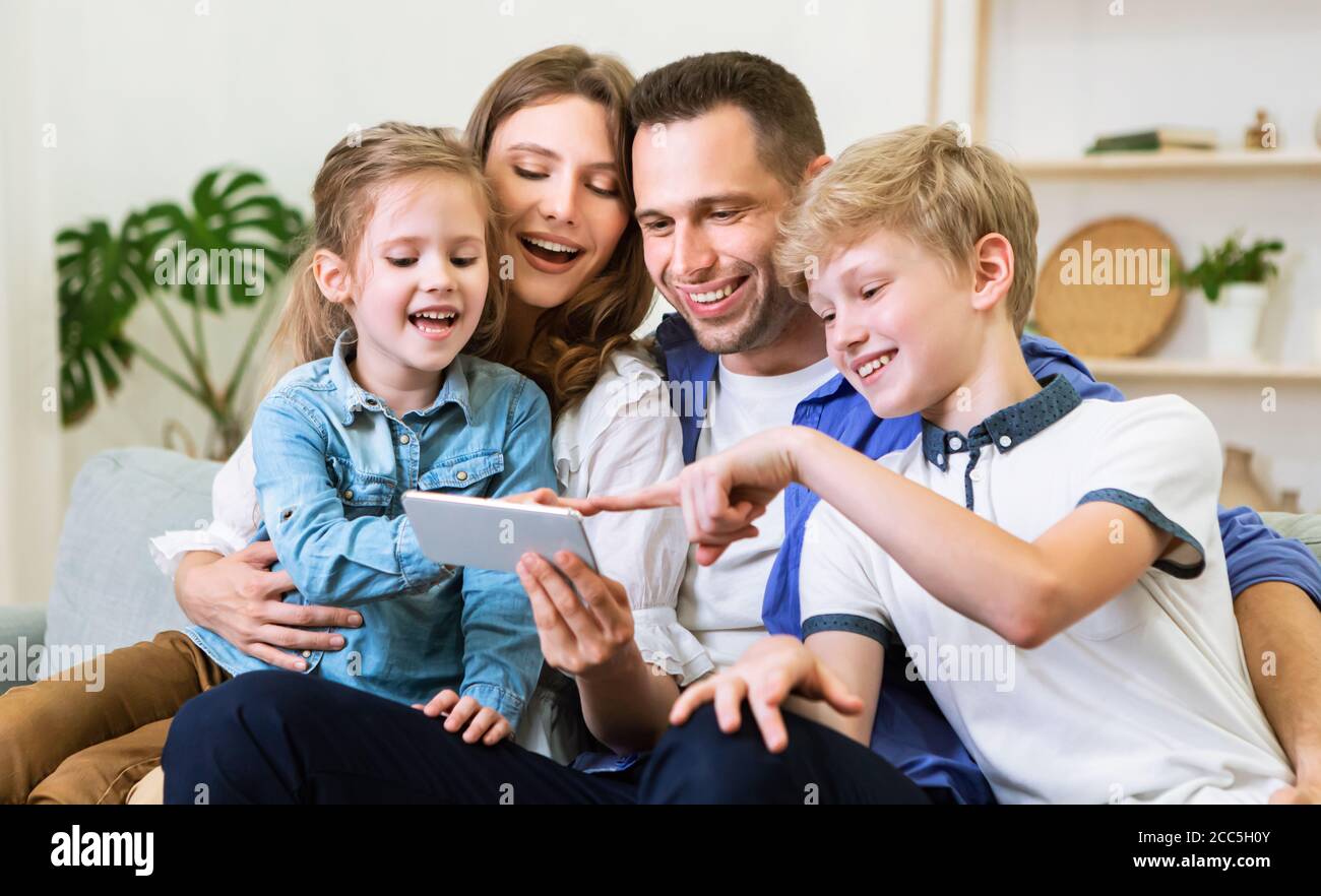 Eltern Und Kinder Mit Handy Sitzen Auf Der Couch Zu Hause Stockfoto