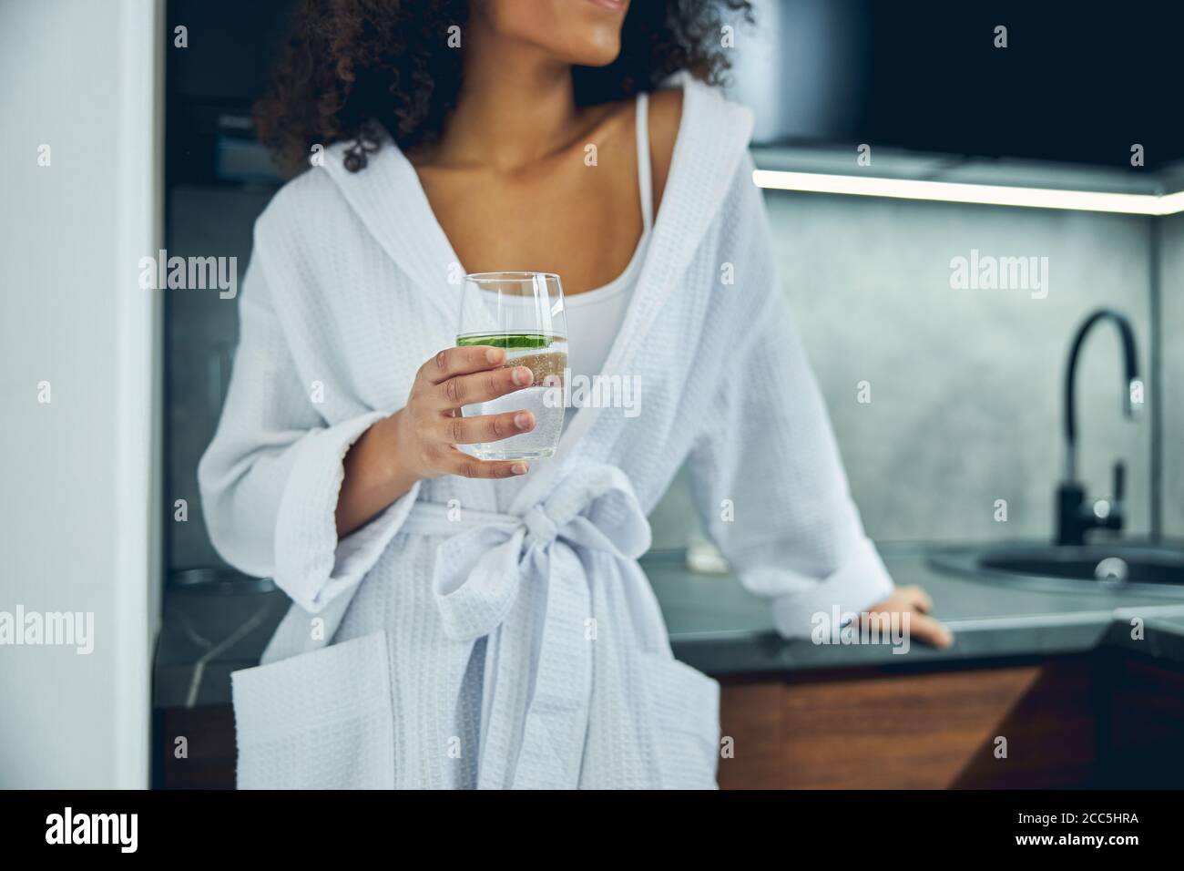 Schlanke Frau hält ein Glas Gurkengetränk Stockfoto
