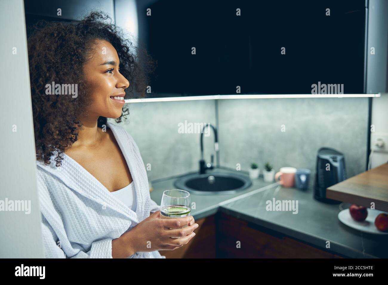 Fröhliche junge Frau, die in der Küche steht Stockfoto