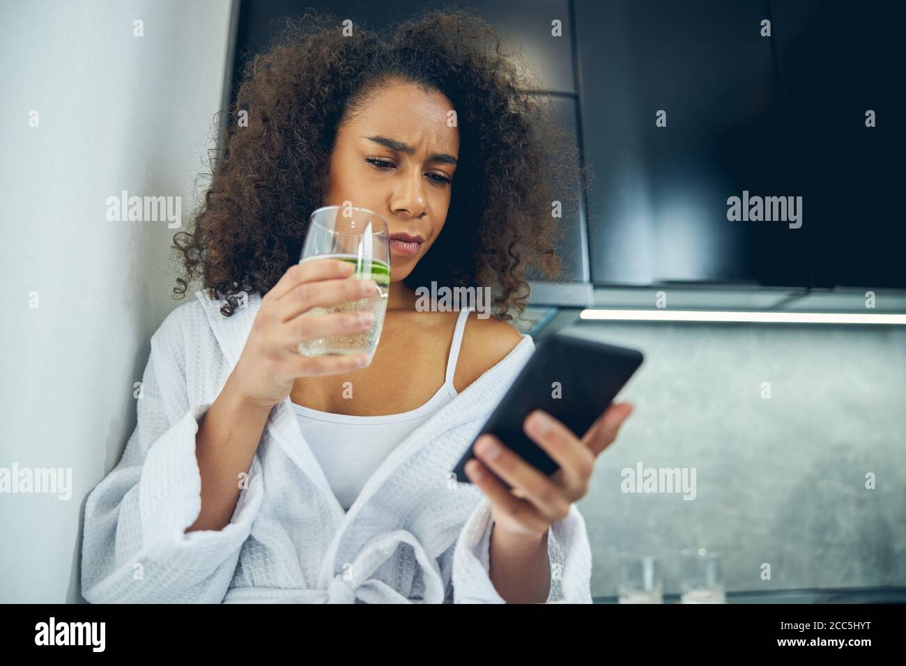 Aufgeregte junge Frau, die auf das Handy schaut Stockfoto