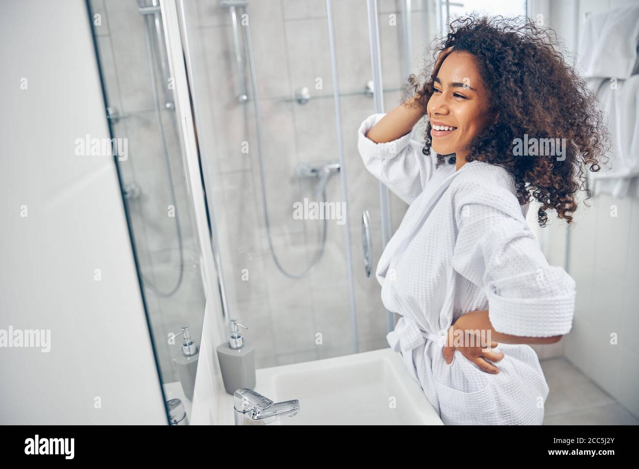 Glückliche junge Frau, die im Badezimmer steht Stockfoto