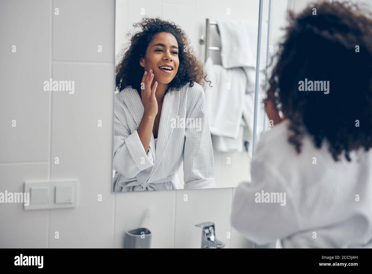 Erfreut Frau Blick auf sich selbst in den Spiegel Stockfoto