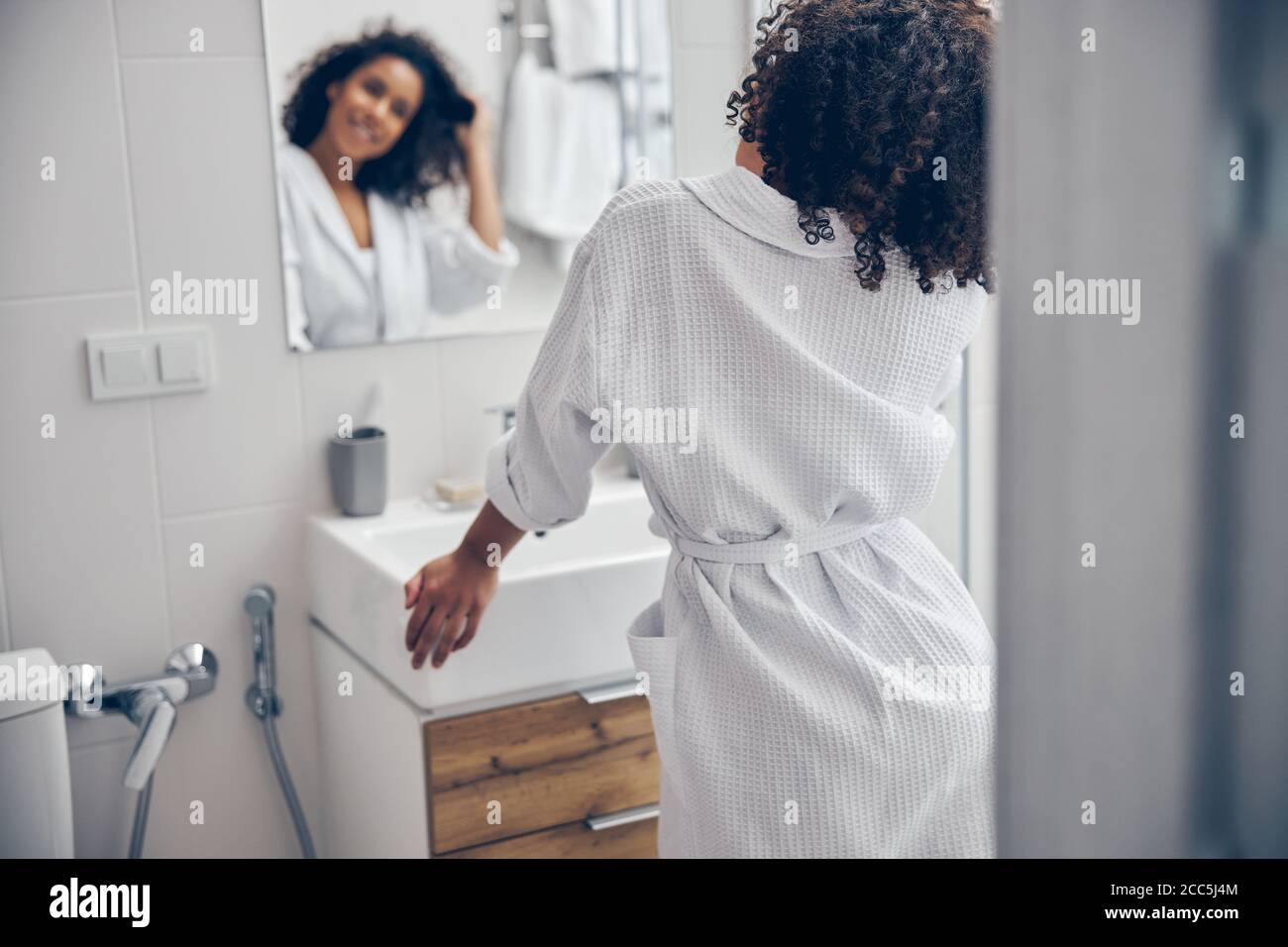 Erfreut Dame berühren ihre Haare vor dem Spiegel Stockfoto
