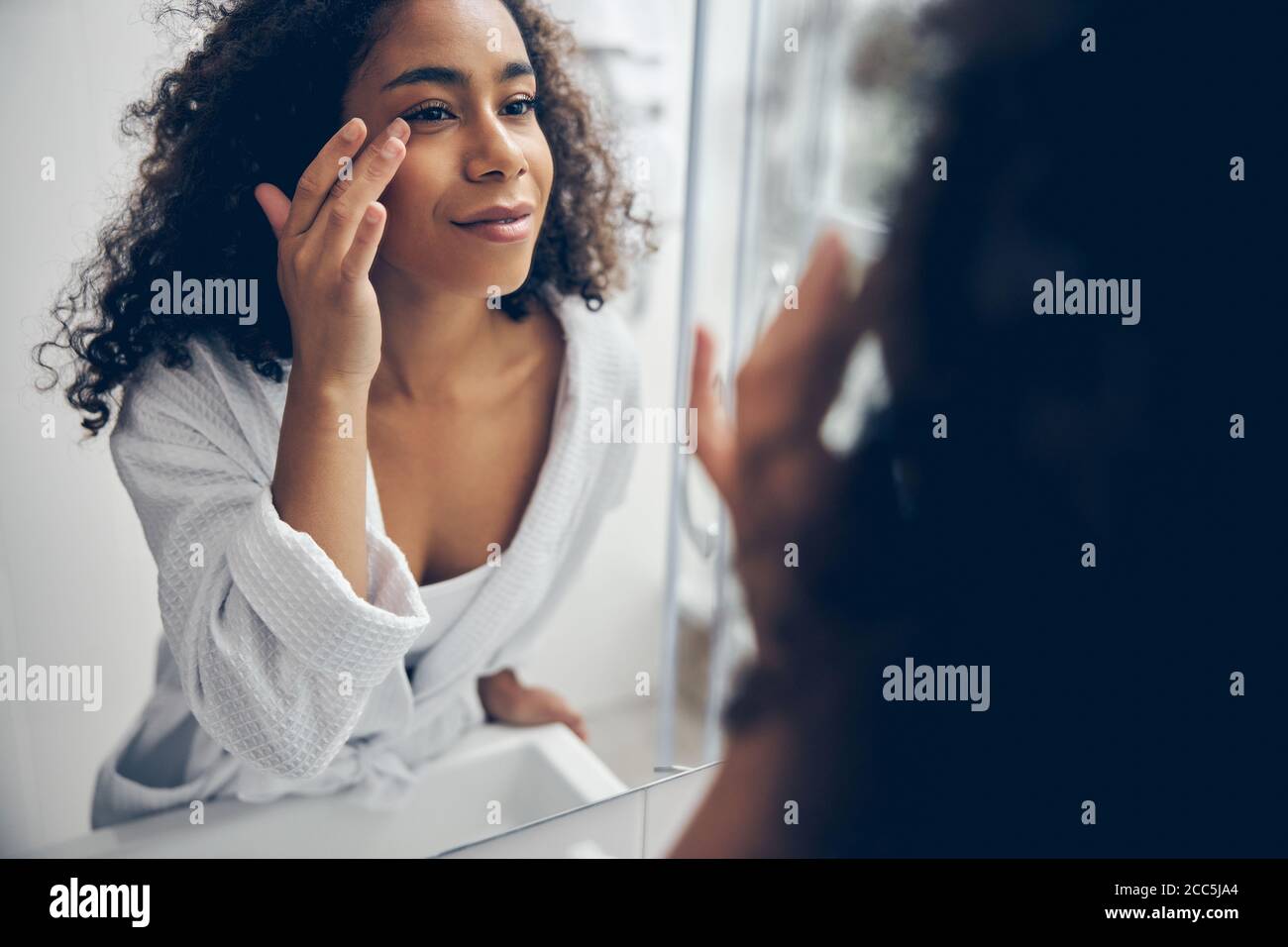 Schöne Frau starrte sich im Spiegel an Stockfoto
