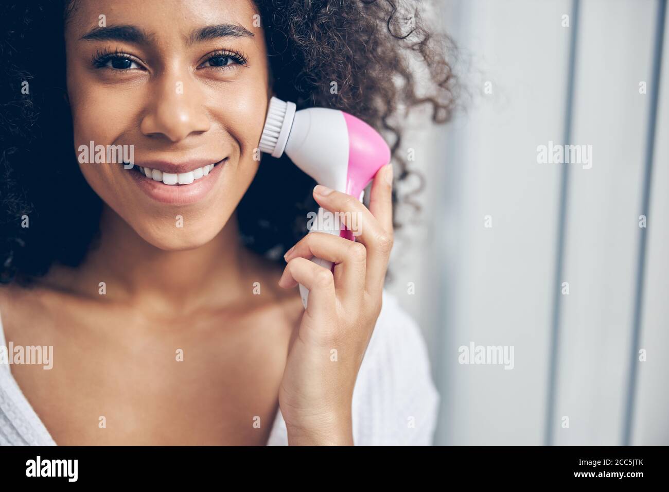 Weibchen hält eine Gesichtsreinigungsbürste mit einer Hand Stockfoto