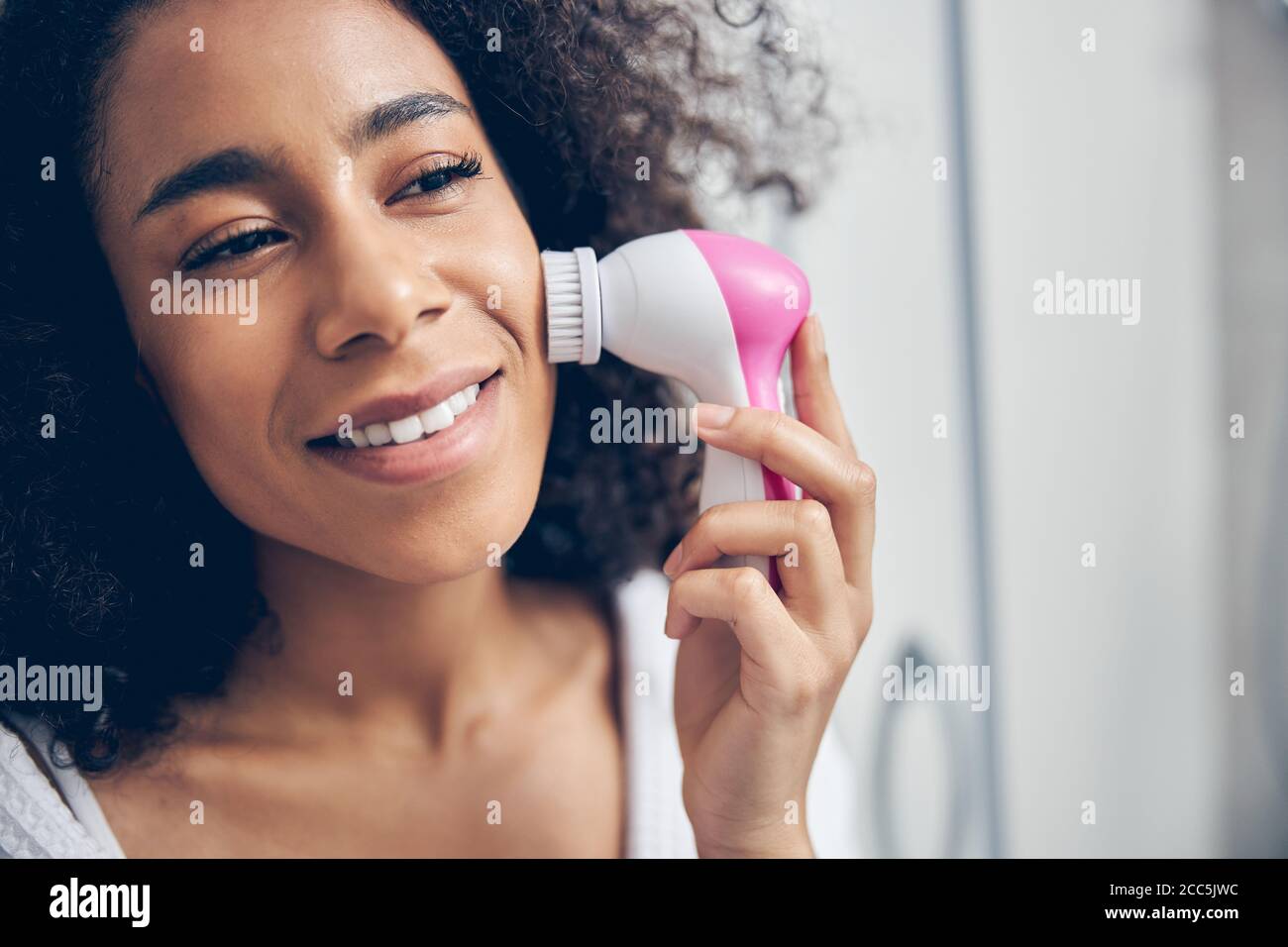 Lächelnd verträumt weiblich Durchführung einer Peeling-Verfahren Stockfoto