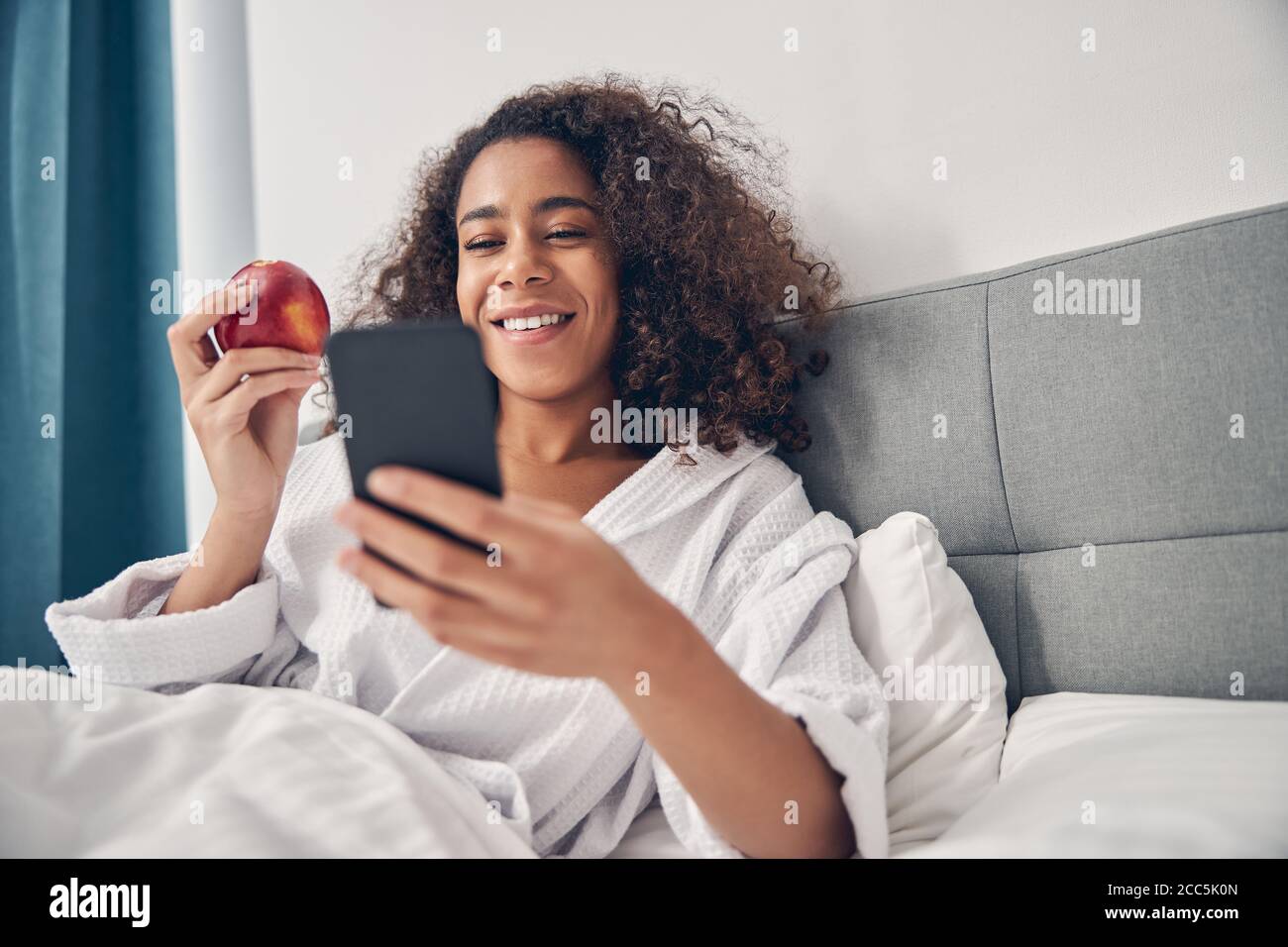 Frau mit einem Gadget im Bett sitzen Stockfoto