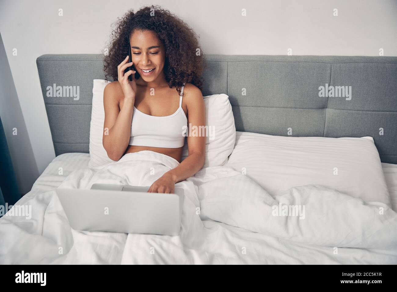 Frau mit einem Telefon im Bett sitzen Stockfoto
