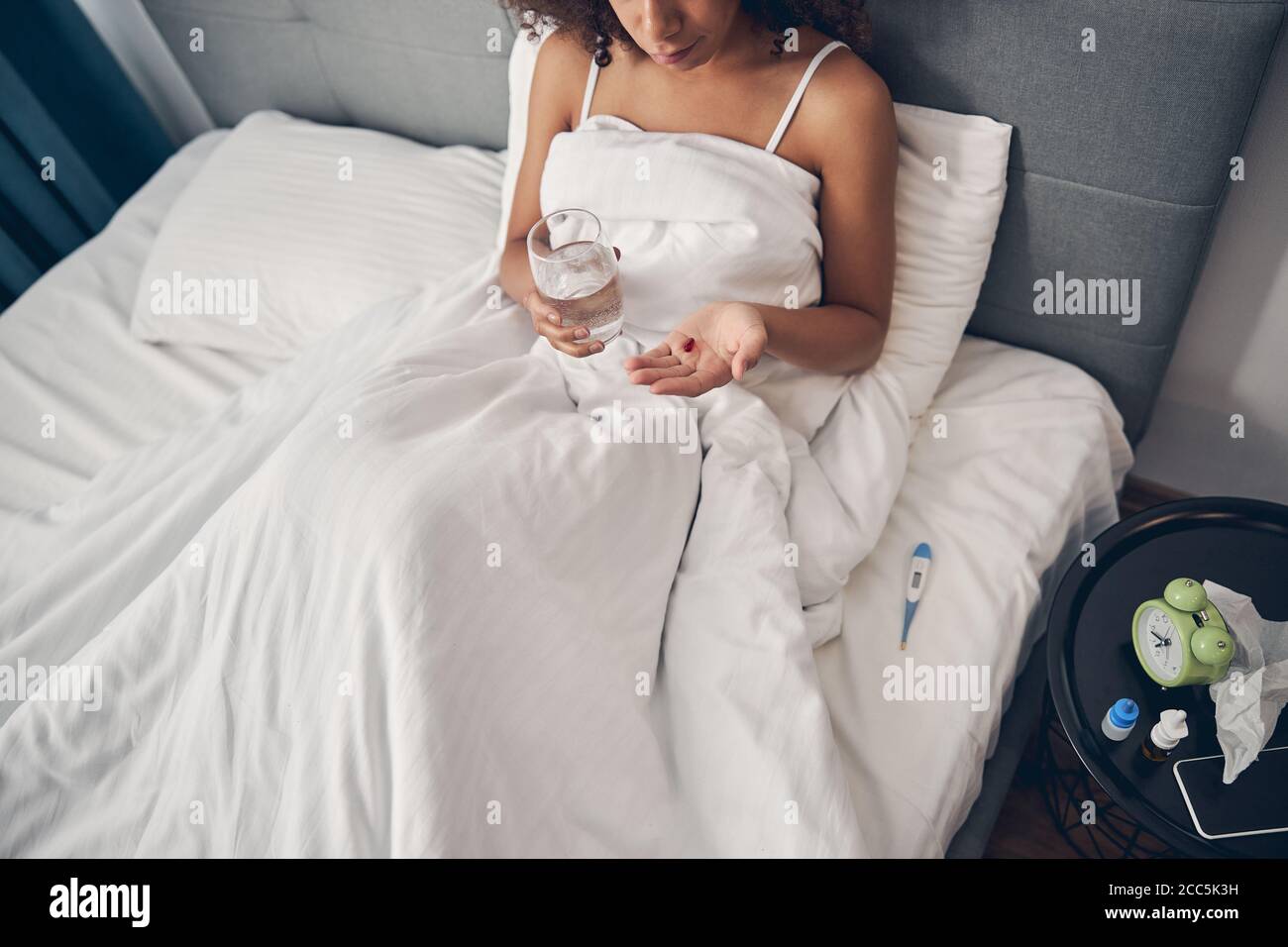 Dunkelhaarige Frau mit einem Glas Wasser im Bett Stockfoto