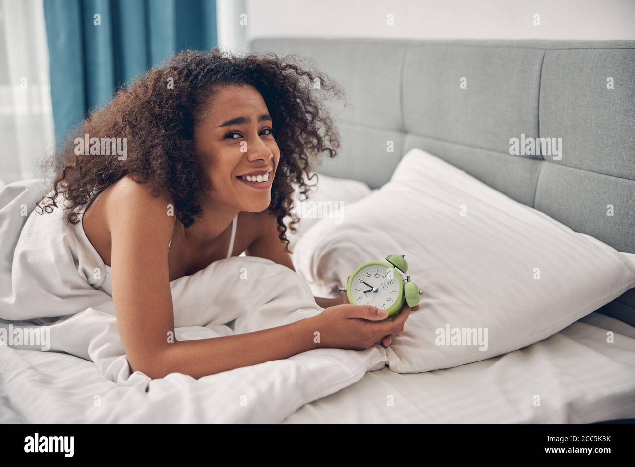 Schöne Frau mit einem glücklichen Lächeln im Bett liegend Stockfoto