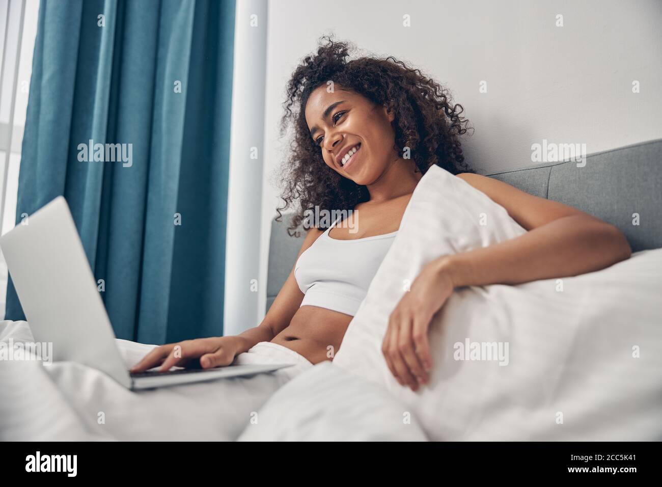 Lächelnde Frau, die auf ihren Laptop-Bildschirm schaut Stockfoto