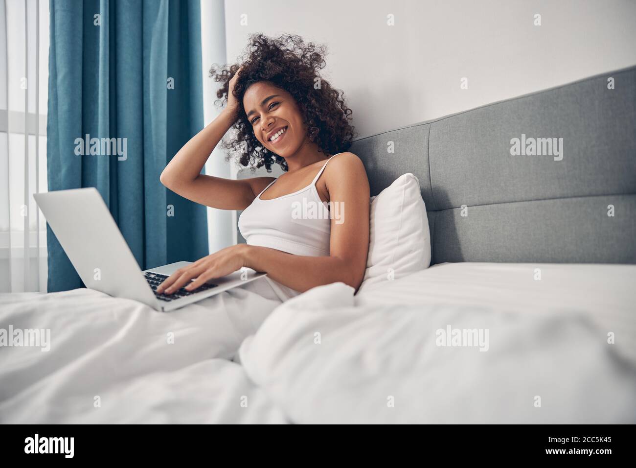 Zufrieden junge Frau Telearbeiter im Bett sitzen Stockfoto