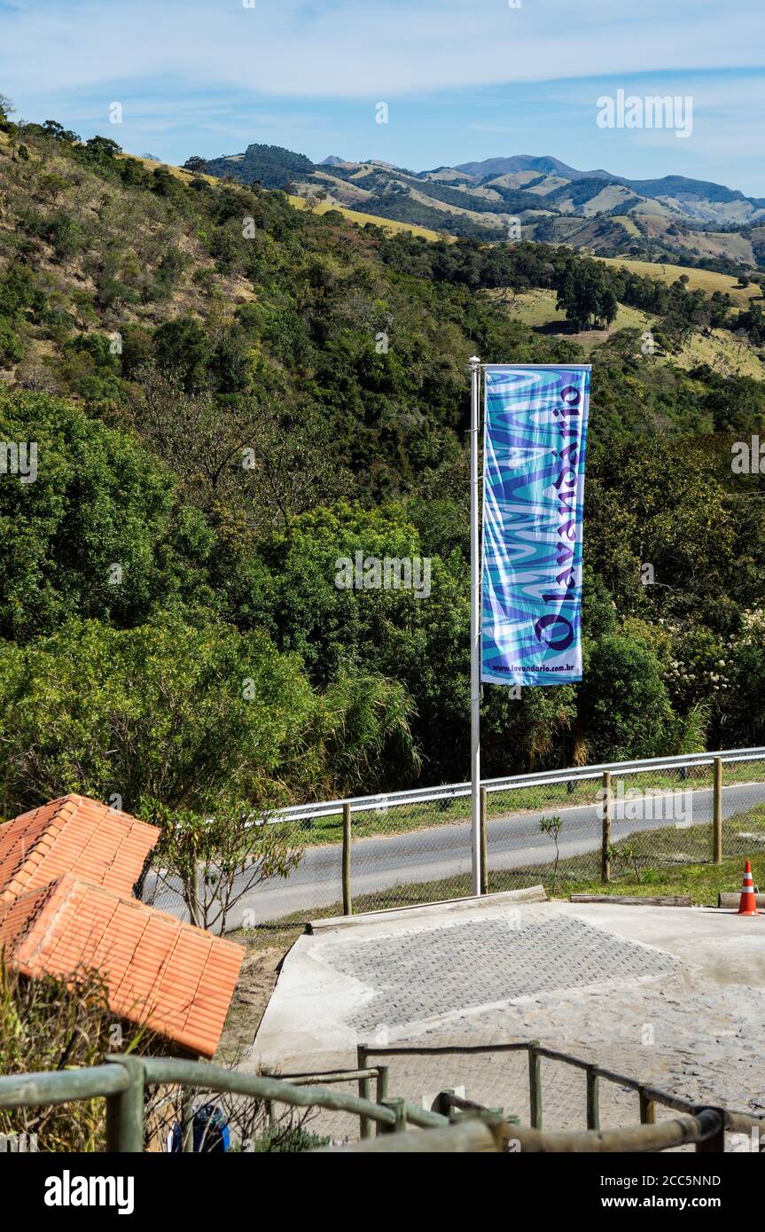 O Lavandario Farmflagge am Eingang/Ausgang der Ranch mit der bergigen Cunha Landschaft im Hintergrund unter sonnigem blauen Himmel. Stockfoto