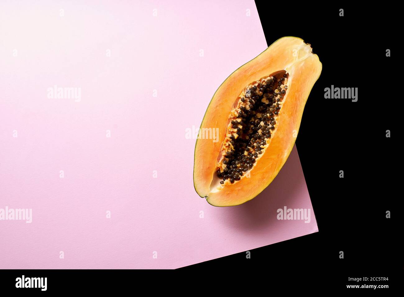 Stillleben Komposition mit Papaya auf rosa und schwarzem Hintergrund. Stockfoto