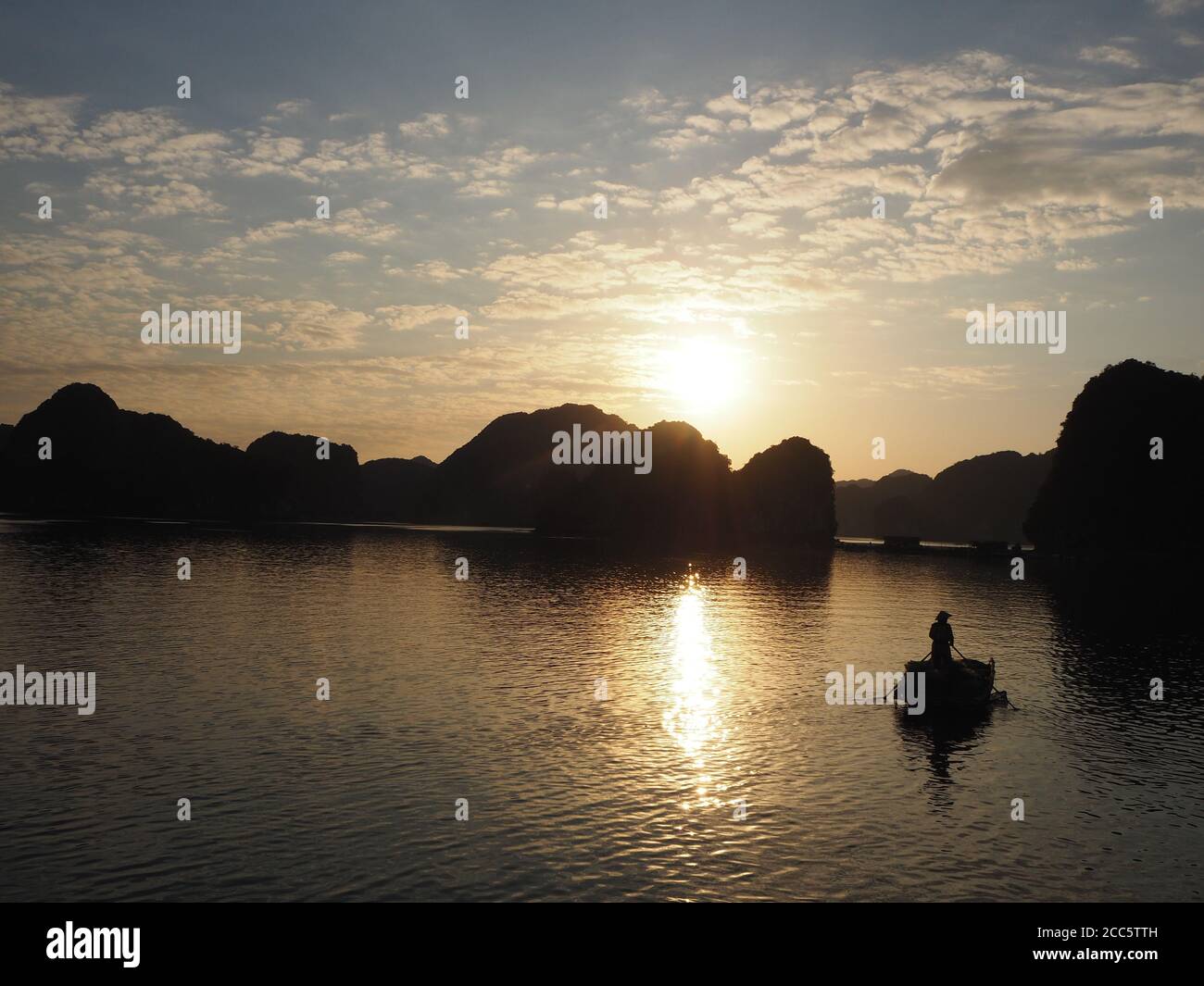 Shadows of a Fisherman Paddling Home bei Sonnenuntergang in Lan Ha Ba, Vietnam Stockfoto