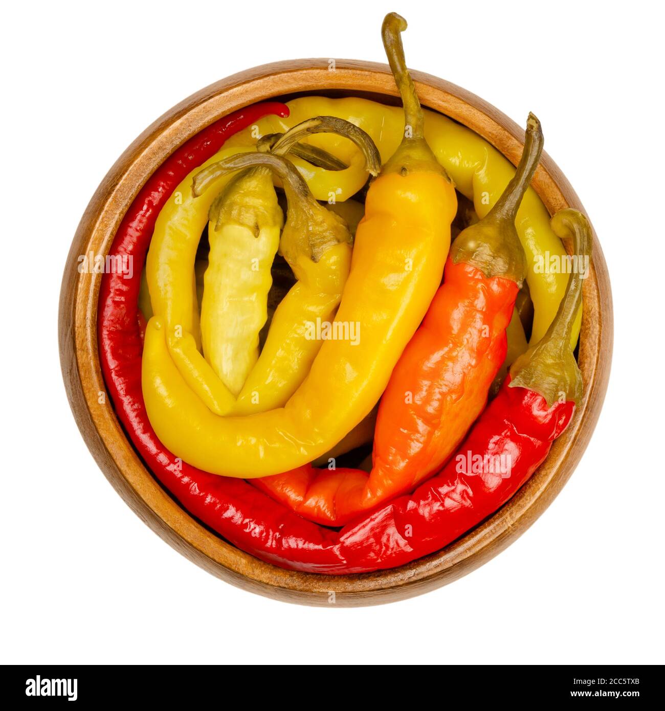 Peperoni Gurken in einer Holzschale. Eingelegte ganze Chilischoten in verschiedenen hellen Farben. Gemüse, in Salzlake konserviert. Capsicum. Stockfoto
