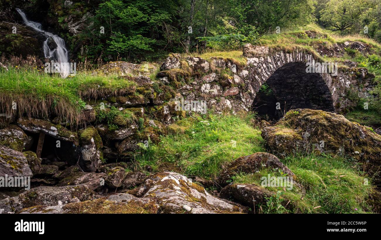 Eine Papppferdbrücke über einen Nebenfluss unter einem Wasserfall am Südufer des Flusses Lyon. Dies ist lokal bekannt als die römische Brücke, obwohl actua Stockfoto