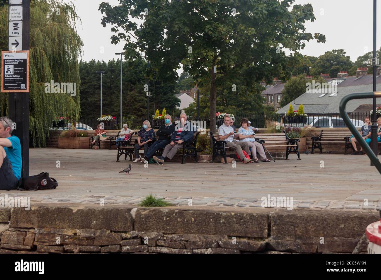 Blick auf nicht identifizierte Personen, die sich neben dem Hotel hinsetzen Der Kanal in Skipton Stockfoto