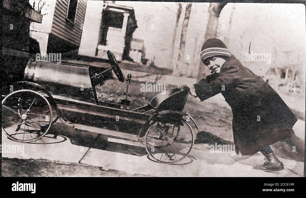 Junge schieben Spielzeugauto bergauf; 1922; Postkarte; Stockfoto