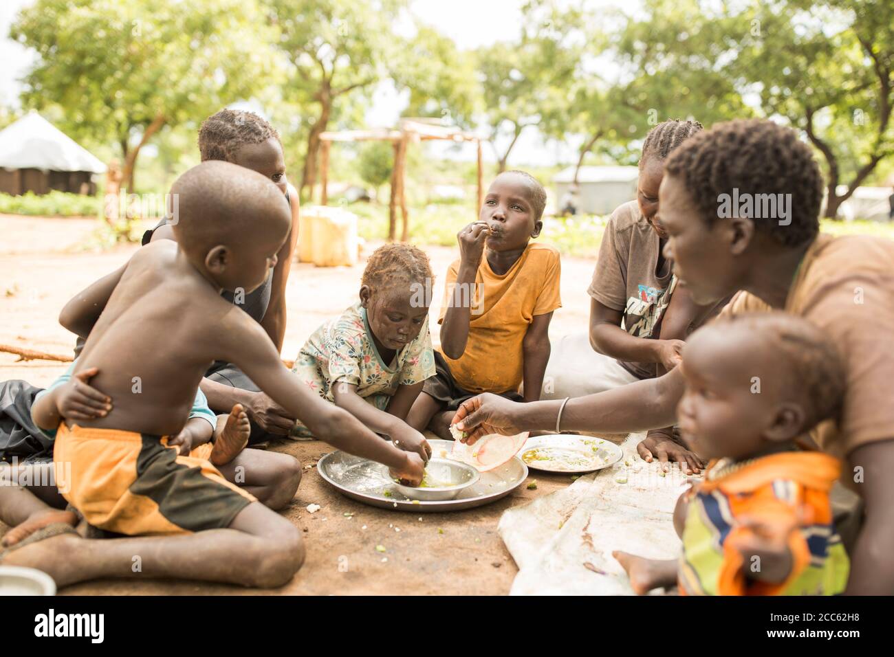 Eine Familie aus dem Südsudan teilt sich eine Mahlzeit in der Palabek Flüchtlingssiedlung im Norden Ugandas, Ostafrika. Stockfoto