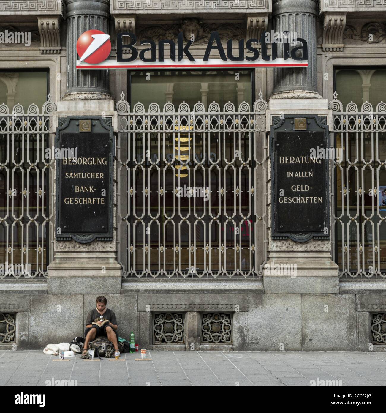 Graz, Österreich. August 2020. Ein Obdachloser sitzt auf dem Bürgersteig vor dem Gebäude der Austria Bank Stockfoto