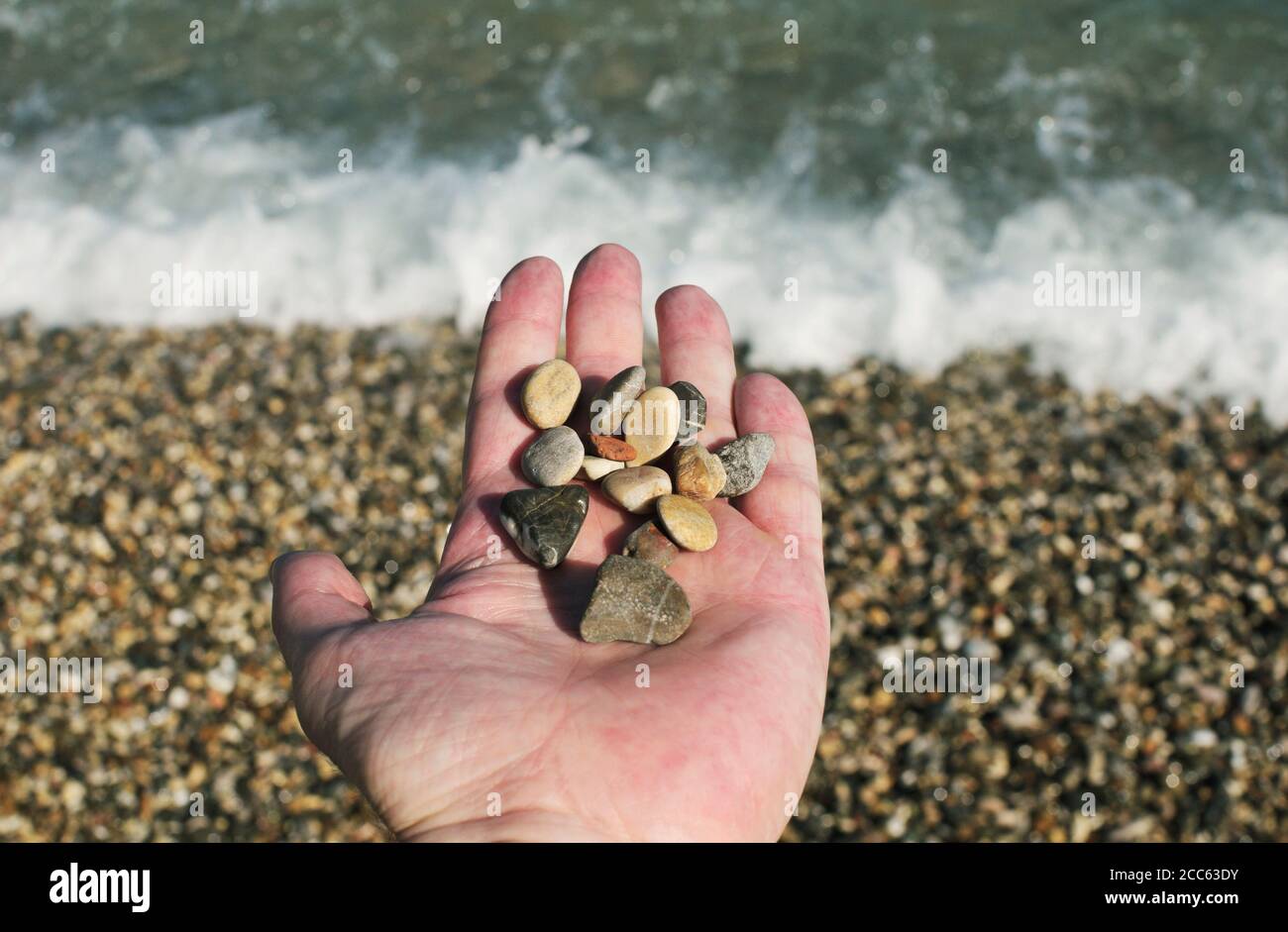 Kleine Strandsteine in der Hand am Meer Stockfoto
