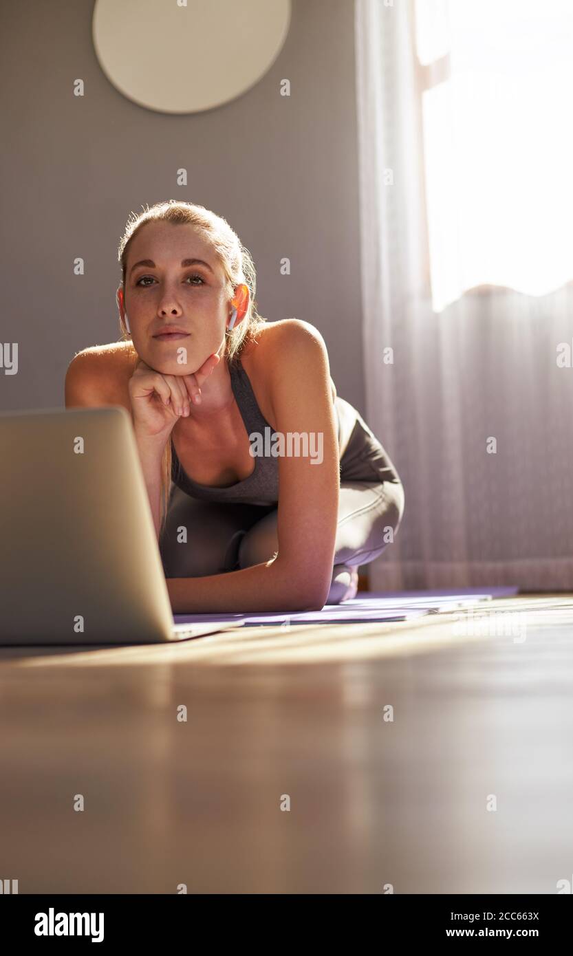 Junge Frau nimmt an Online-Fitness-Kurs vor Von Laptop, der auf die Kamera schaut Stockfoto