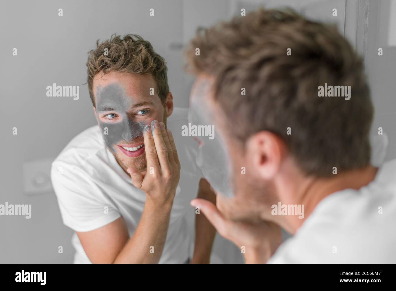 Männer Schönheit kaukasischen jungen Mann Anwendung Schlamm Ton Detox Maske auf Gesicht. Gesichtsbehandlung mit Holzkohle für die männliche Hautpflege Stockfoto