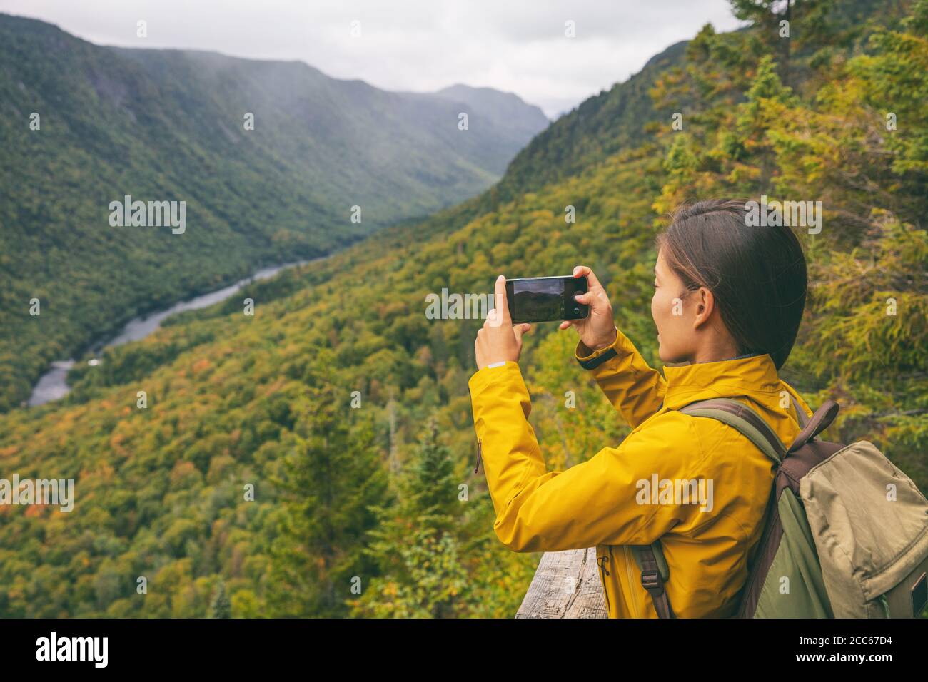 Wanderung Frau Wanderer fotografieren mit Telefon des Flusses Blick von der Spitze des Weges Wandern im Parc National de la Jacques Cartier, Quebec, Kanada Herbst Reise Stockfoto