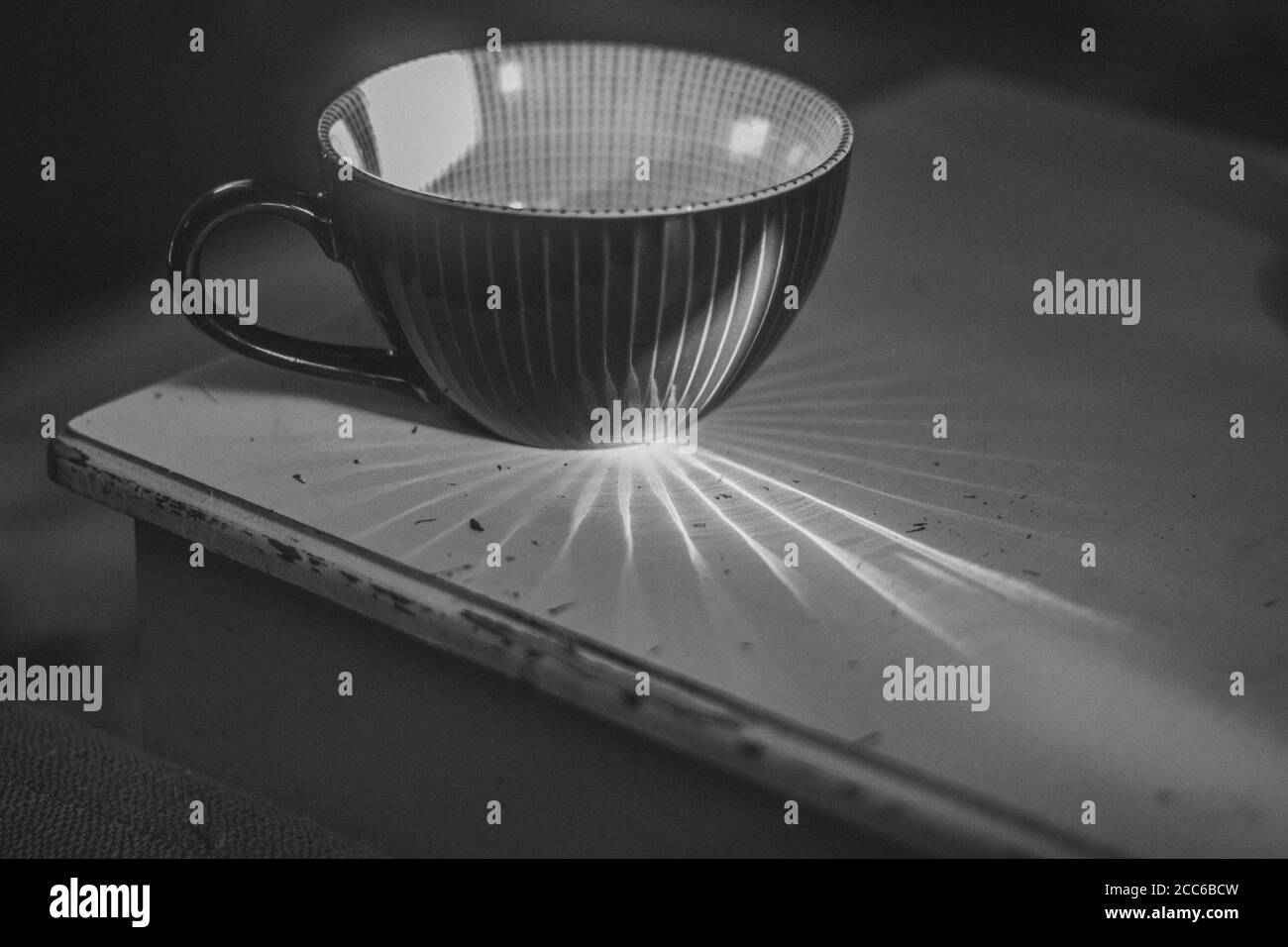 Schwarz-Weiß-Kaffeetasse auf Vintage-Tisch mit Stern Motiv durch Sonnenlicht geschaffen Stockfoto