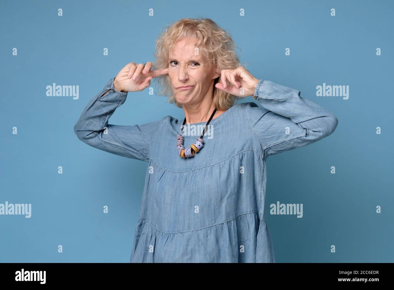 Ältere ältere Frau, die vor Unmut Ohren bedeckt. Stockfoto