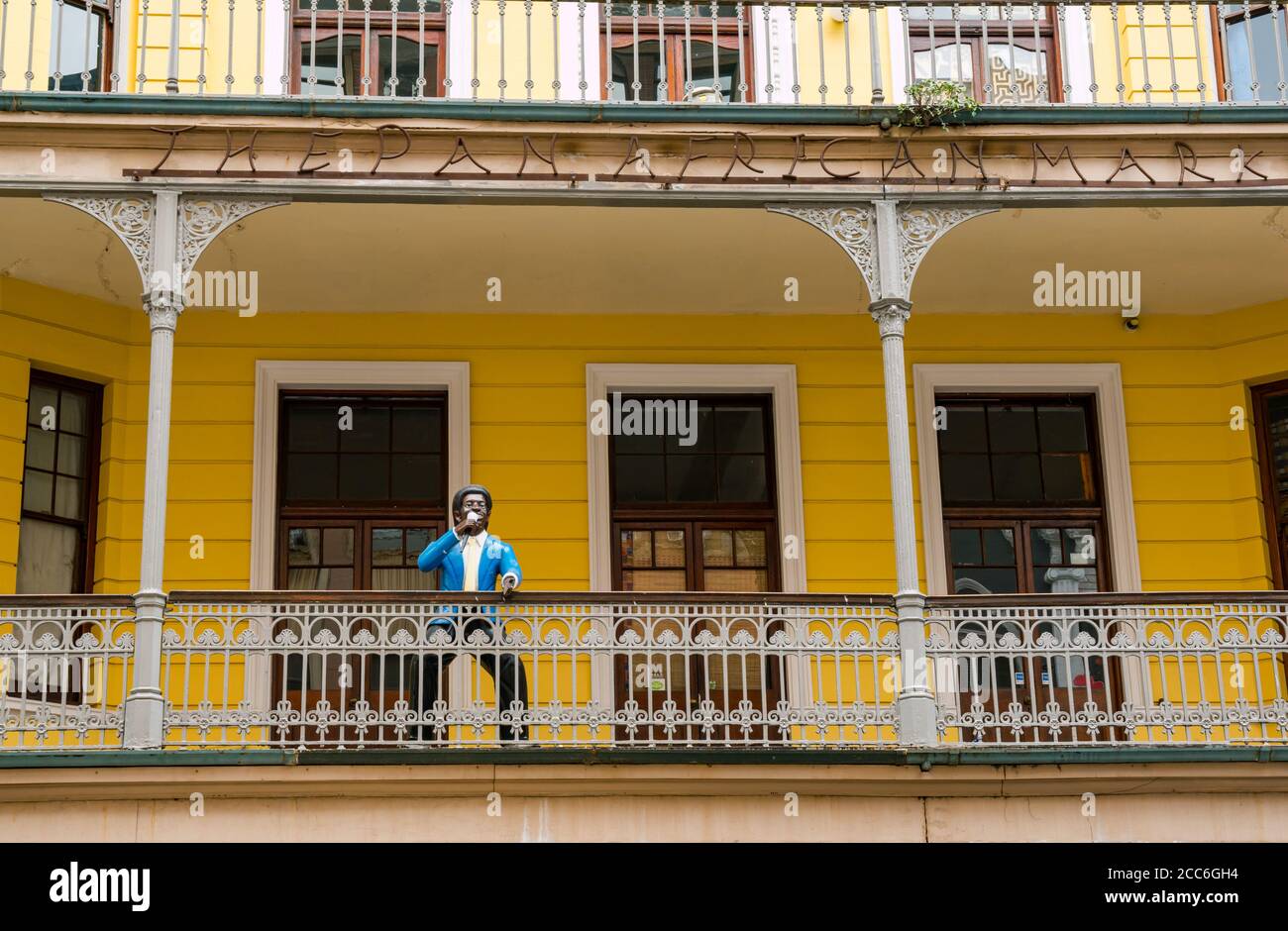Altes Gebäude im Kolonialstil mit schwarzer männlicher Figur, die auf dem Balkon, Pan African Market, Long Street, Kapstadt, Südafrika ins Mikrofon spricht Stockfoto