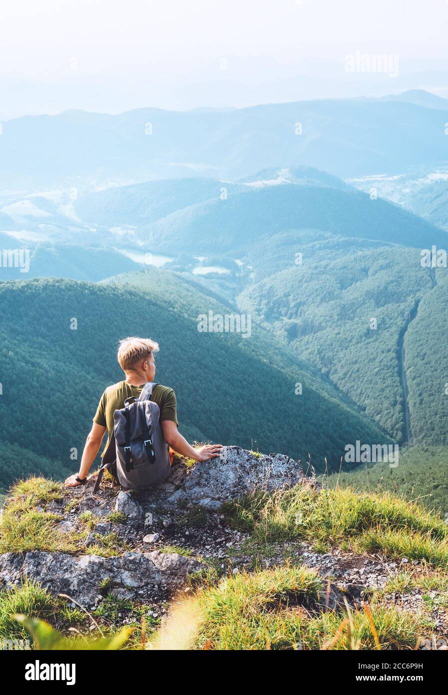 Junger Mann Tourist Rest auf der Spitze des Hügels mit Wunderschönes Talpanorama Stockfoto