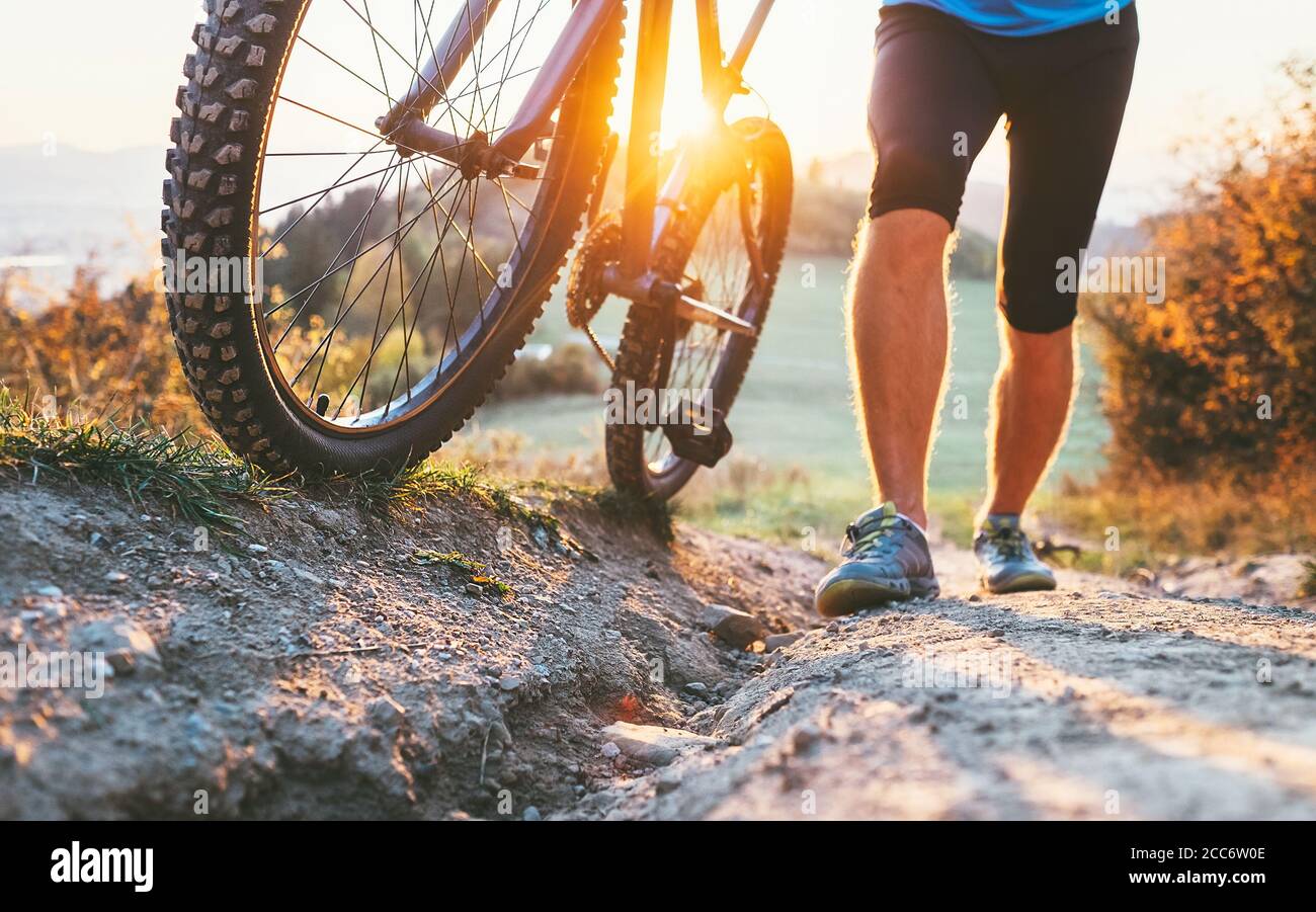 Junger Radfahrer Mann schob ein Mountainbike den Hügel hinauf Bild aus der Nähe. Aktive Abenteuerreise mit dem Fahrrad. Stockfoto