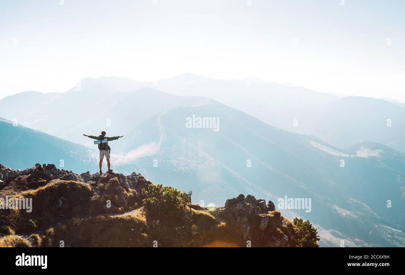 Bergwanderer mit Rucksack kleine Figur steht auf dem Berggipfel Stockfoto
