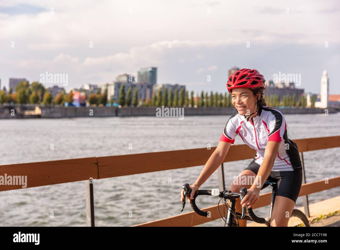 Urban Biking Mädchen Reiten Rennrad Radfahren in der Stadt. Glücklicher Radfahrer mit Downtown Hintergrund am St. Lawrence River, Montreal, Kanada Stockfoto