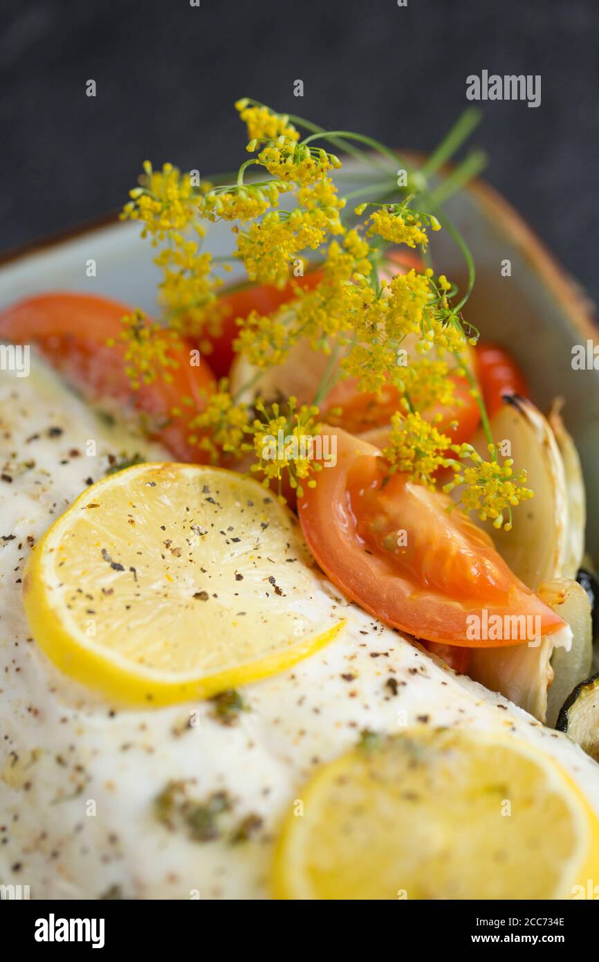 Ein Filet aus einer Linie gefangen wilden Bass, Dicentrarchus labrax, das mit Gemüse, Zitronenscheiben, Olivenöl und Butter geröstet und gewürzt w Stockfoto